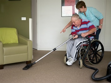 A person in a wheelchair vacuuming their house.