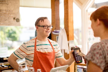 A man working in a cafe, serving a customer.