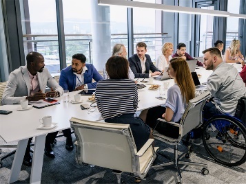 A diverse group of people having a meeting in an office around a large table.
