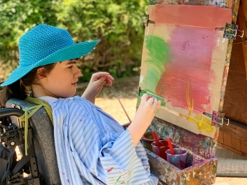 A young person painting on a board.